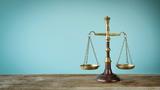 Scales of justice on the wooden table and a blue background, photo by seb_ra/Getty Images