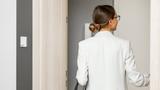Back of woman walking through door in workplace building, photo by RossHelen/Getty Images