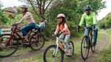 Multi-racial family riding their bikes around a public park, photo by SolStock/Getty Images