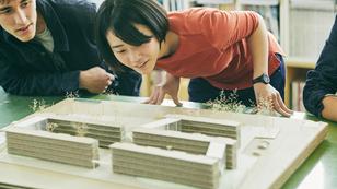 Architecture students looking at a model of buildings, photo by D76MasahiroIKEDA/Getty Images